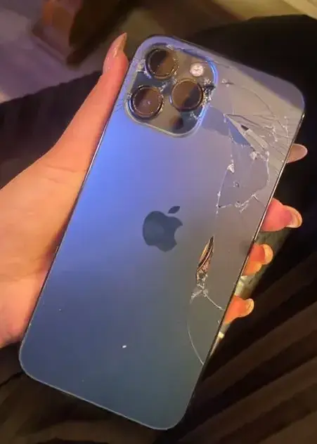 Femme tenant dans sa main un iPhone 14 avec le chassis arrière cassé