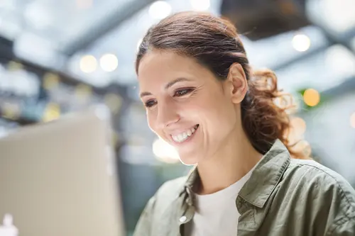 une femme contente d'utiliser son ordinateur après un service de réparation informatique chez numerichip